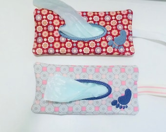 May include: Two fabric tissue box covers with a blue footprint design. One cover is red with white polka dots and the other is gray with pink polka dots.