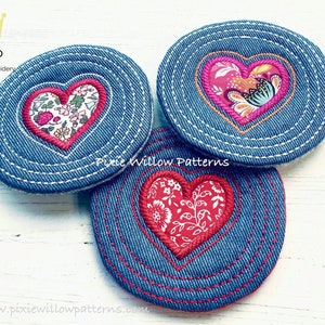 Peut inclure: Trois dessous de verre en denim avec des motifs de cœur brodés. Chaque dessous de verre présente une base en denim bleu avec un cœur rouge. Les cœurs sont remplis de motifs floraux et soulignés de coutures rouges. Les dessous de verre sont ronds.