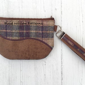 May include: A brown and plaid zippered pouch with a brown leather strap and a silver clasp. The pouch has the text "Pixie Willow Patterns" printed on the front.