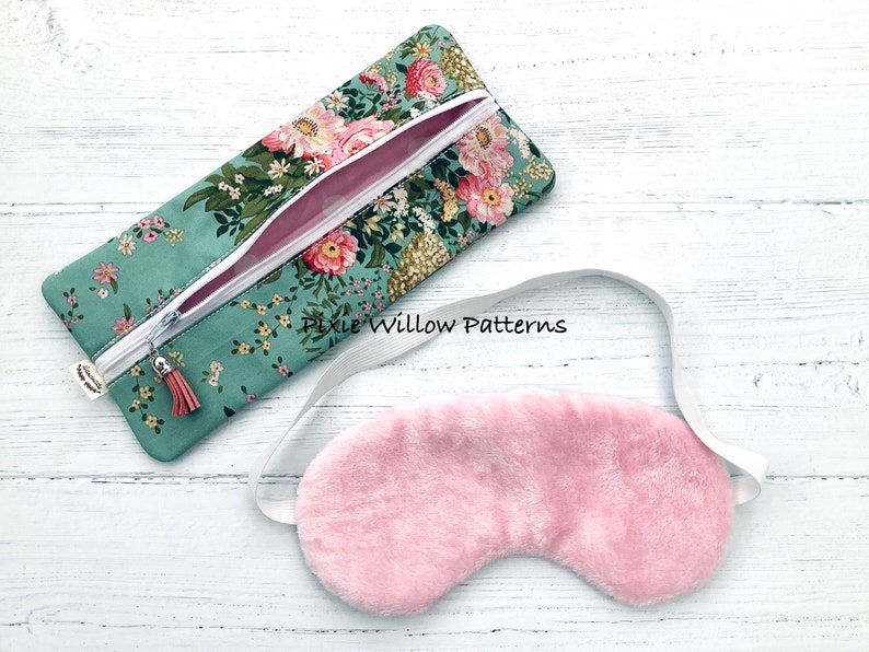 May include: A teal zippered pouch with a floral print and a pink tassel. A pink sleep mask with a white elastic strap is next to the pouch. The text "Pixie Willow Patterns" is visible on the pouch.