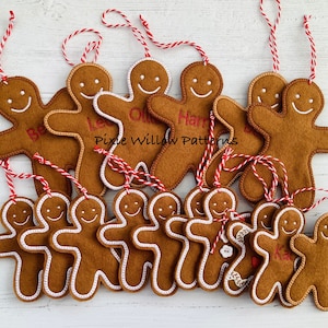 May include: A selection of brown gingerbread man decorations with white icing and red and white twine hanging loops. Some have embroidered names. The text "Pixie Willow Patterns" is also visible.