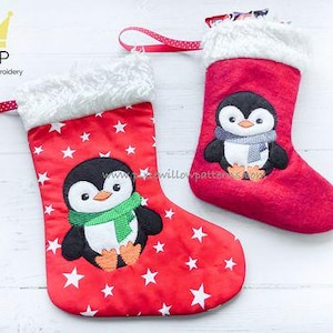 May include: Two red Christmas stockings with white stars and a penguin design. The larger stocking has a green scarf and the smaller stocking has a blue scarf.