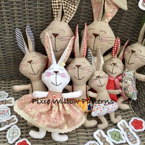 Puede incluir: Un grupo de siete juguetes de conejo de tela hechos a mano, cada uno con patrones y colores de tela únicos. Los conejos están sentados en una silla de mimbre con una guirnalda de tela de hojas y flores.