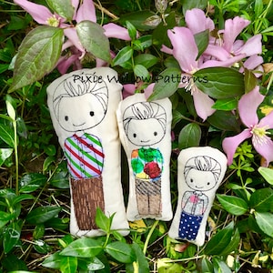 May include: Three fabric dolls with embroidered details, each depicting a smiling figure in different outfits. The dolls are set against a backdrop of green foliage and pink flowers. The text "Pixie Willow Patterns" is visible.