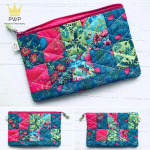 Könnte beinhalten: Eine rosa und blaue Patchwork-Zipper-Tasche mit Blumenmuster. Die Tasche ist gesteppt und hat einen rosa Reißverschluss.