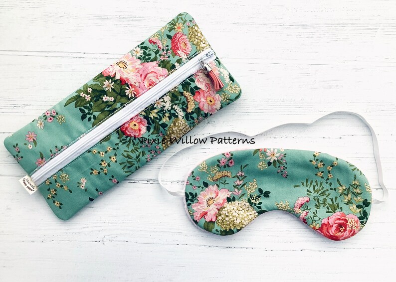 May include: A green floral eye mask and matching zipped pouch. The eye mask has a white elastic strap. The pouch has a white zipper and a pink tassel.