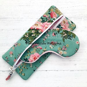 May include: A teal blue eye mask with a floral print and the text "do not disturb" embroidered on it. The eye mask is in a matching teal blue zippered pouch with a floral print.
