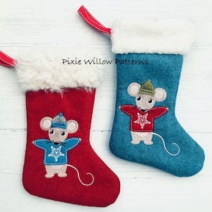 Puede incluir: Dos calcetines de Navidad con un diseño de ratón. El calcetín de la izquierda es rojo con un puño de piel sintética blanca y un ratón blanco que lleva un suéter azul con un diseño de copo de nieve. El calcetín de la derecha es azul con un puño de piel sintética blanca y un ratón blanco que lleva un suéter rojo con un diseño de estrella. El texto "Pixie Willow Patterns" es visible en la imagen.