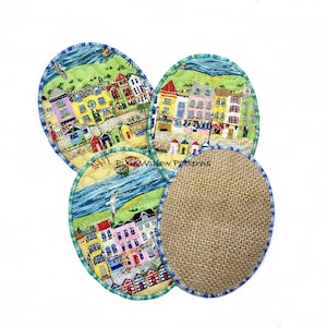 Pode incluir: Conjunto de quatro bases ovais. Três apresentam uma cena colorida de cidade costeira com edifícios, cabanas de praia e um oceano azul. A quarta tem uma textura natural de serapilheira. Cada base tem uma borda costurada azul e verde.