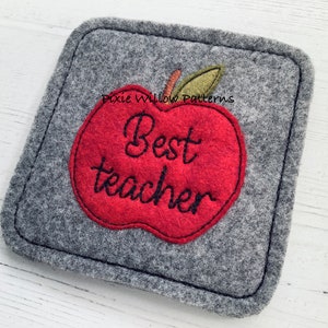 May include: A gray felt coaster with a red apple design that says "Best teacher" in black embroidery.