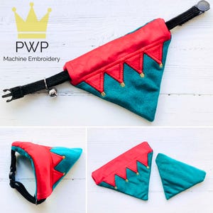 May include: A red and teal dog bandana with gold embroidered crowns. The bandana is attached to a black collar with a silver bell.