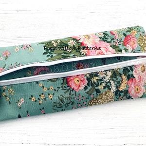 May include: A teal zippered pouch with a floral print and a white zipper. The pouch has a tassel pull and the text "Pixie Willow Patterns" is embroidered on the front.