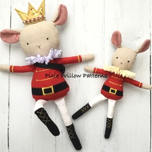 Könnte beinhalten: Zwei Plüsch-Maus-Spielzeuge, die als Nussknacker verkleidet sind. Die größere Maus trägt eine goldene Krone und einen weißen Rüschenkragen. Die kleinere Maus trägt einen weißen Rüschenkragen. Beide Mäuse tragen rote und goldene Nussknacker-Kostüme mit schwarzen Stiefeln.