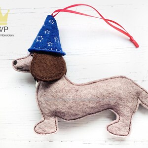 Pode incluir: Um dachshund de feltro usando um chapéu de mago azul e branco com padrão de estrelas com uma fita vermelha presa.