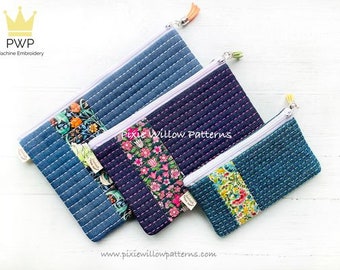 May include: Three quilted zipper pouches in different sizes. The largest pouch is blue denim with a floral print panel. The middle pouch is dark blue with a pink floral print panel. The smallest pouch is teal blue with a floral print panel. All pouches have white zippers and a tassel pull.