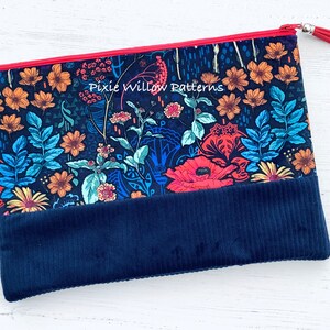 Op de afbeelding: Een blauwe ritszak met een bloemenprint en een donkerblauwe corduroy bodem. De tas heeft een rode rits en een zilveren kwast. De tekst "Pixie Willow Patterns" is op de tas gedrukt.