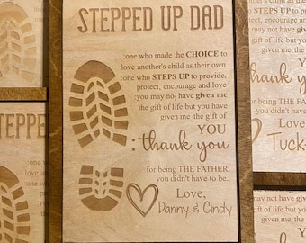 May include: A wooden framed sign with the words "STEPPED UP DAD" engraved at the top. The sign includes a shoe print, a heart, and the words "thank you". The text reads, "for being THE FATHER you didn't have to be."