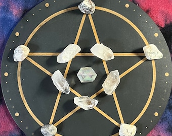 May include: A black wooden circle with a gold pentacle design and eight clear quartz crystals and one iridescent crystal placed on the points of the pentacle.