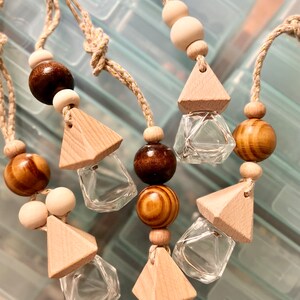 May include: Set of six car air fresheners with wooden triangle charms and clear glass bottles. Each charm is attached to a string with wooden beads in brown, tan, and natural colors.