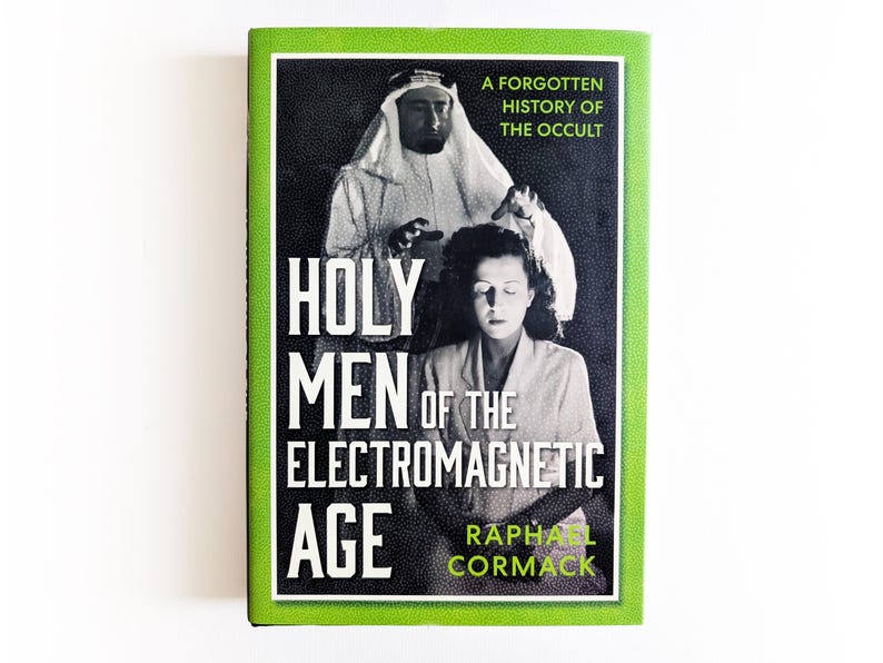 May include: A hardcover book titled Holy Men of the Electromagnetic Age: A Forgotten History of the Occult by Raphael Cormack. The cover features a black and white photograph of a person in a head covering and another person, with bright green borders.