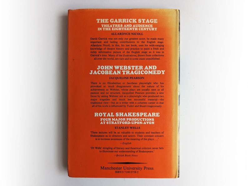 May include: A red book cover with the title "The Garrick Stage: Theatres and Audience in the Eighteenth Century" by Allardyce Nicoll. The book also features the titles "John Webster and Jacobean Tragicomedy" by Jacqueline Pearson and "Royal Shakespeare: Four Major Productions at Stratford-upon-Avon" by Stanley Wells. The book is published by Manchester University Press.
