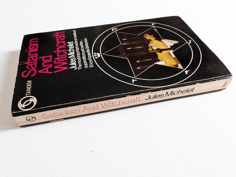 May include: A vintage copy of "Satanism And Witchcraft" by Jules Michelet. The book has a black cover with white and pink lettering, and a pentagram design. Published by Tandem, it is a historical work.