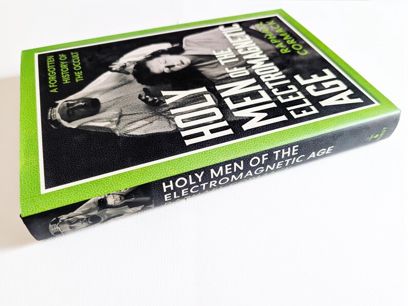 May include: A hardcover book titled Holy Men of the Electromagnetic Age by Raphael Cormack. The cover features a black and white photograph of a person in traditional headwear, framed by a bright green border with the text A Forgotten History of the Occult.