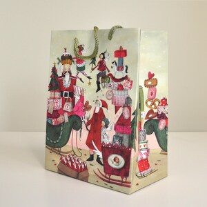 Könnte beinhalten: Eine dekorative Geschenktüte mit weihnachtlichem Thema. Die Tasche zeigt Illustrationen eines Nussknackers, des Weihnachtsmanns und anderer Weihnachtsfiguren. Die Tasche hat grüne Kordelgriffe und ist ideal für Geschenke.