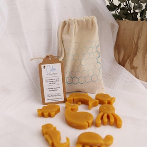 May include: A natural beeswax sensory set with animal shapes, a drawstring bag, and a tag that reads "Calm In Your Palm". The set includes a whale, fish, octopus, and other sea creatures.