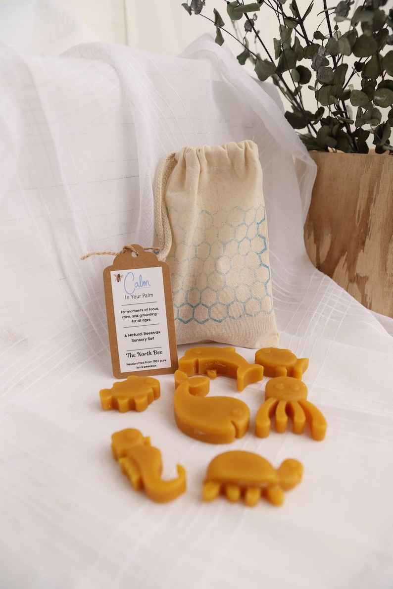 May include: A natural beeswax sensory set with animal shapes, a drawstring bag, and a tag that reads "Calm In Your Palm". The set includes a whale, fish, octopus, and other sea creatures.
