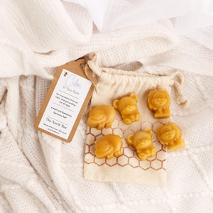 May include: A natural beeswax sensory set with animal shapes, including bears and lions, in a small drawstring bag. The set is labeled "Calm in Your Palm" and is handmade from 100% pure food-grade beeswax.