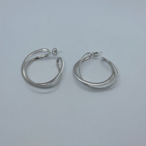 May include: A pair of silver hoop earrings with a double-loop design.