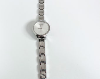 May include: A silver-toned wristwatch with a white face and a silver metal band.