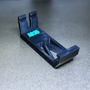 May include: A black plastic phone stand with a geometric design and the text "A020" printed on the side.