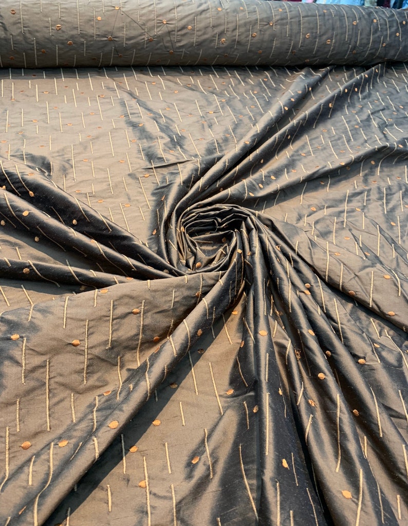 May include: Dark grey fabric with a subtle sheen, patterned with vertical lines and small dots in a lighter gold colour. The fabric is gathered and folded, creating a textured appearance.