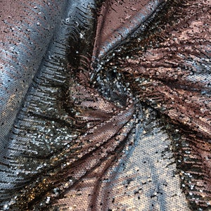 May include: A fabric with a gradient of silver, black, and rose gold sequins. The sequins are sewn onto a mesh backing.