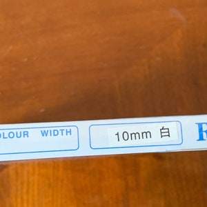 K&ouml;nnte beinhalten: Eine wei&szlig;e Verpackung mit blauem Text, der "Polyester Boning, Colour, Width, 10mm 白, RIGILENE" lautet.