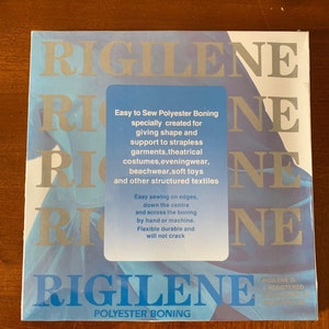 K&ouml;nnte beinhalten: Eine blaue und wei&szlig;e Packung Rigilene Polyester-St&uuml;tzstoff. Die Packung enth&auml;lt den Text: "Einfaches N&auml;hen von Polyester-St&uuml;tzstoff, speziell entwickelt f&uuml;r Formgebung und Halt f&uuml;r tr&auml;gerlose Kleidungsst&uuml;cke, Theaterkost&uuml;me, Abendgarderobe, Strandbekleidung, Pl&uuml;schtiere und andere strukturierte Textilien. Einfaches N&auml;hen an den Kanten, unten in der Mitte und &uuml;ber den St&uuml;tzstoff, von Hand oder mit der Maschine. Flexibel, strapazierf&auml;hig und rei&szlig;fest. Rigilene ist eine eingetragene Marke von Selkirk."