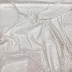 May include: White fabric with a subtle shimmer, likely sequins, creating a textured and sparkly surface.