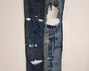 May include: Two pieces of blue denim fabric with holes and tears. The fabric is worn and faded, showing signs of age and use.
