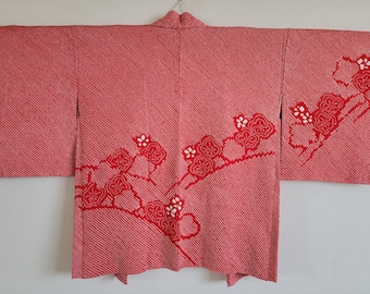Puede incluir: Un kimono japonés rojo y blanco con un patrón floral. El kimono está hecho de una tela suave y texturizada y tiene un diseño tradicional.