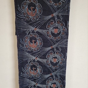May include: A black fabric with a repeating pattern of stylized birds in a circle with orange and blue accents. The fabric has a textured surface.