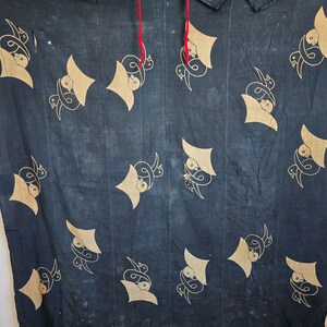 May include: A dark blue fabric with a repeating pattern of stylized birds in a light brown color. The fabric has a textured, slightly worn look.