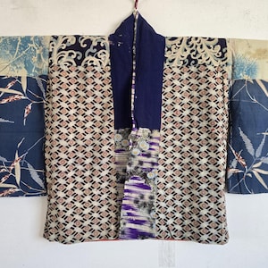 May include: A patchwork kimono jacket featuring a variety of blue, white, and purple fabric panels. The garment displays a mix of patterns including geometric diamond shapes, floral motifs, bamboo stalks, and wave designs with a solid dark blue collar.