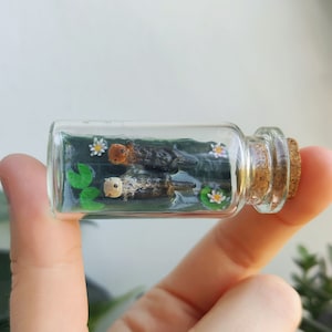 Två uttrar som håller varandra i handen i en glasflaska / unik miniatyrfigur / handgjort konstverk
