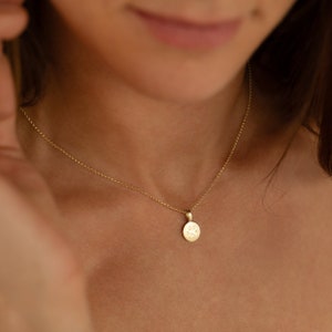 May include: A gold chain necklace with a small, round pendant featuring a paw print design.