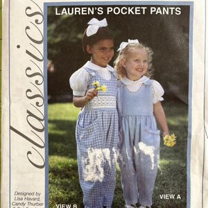 May include: A sewing pattern titled "Lauren's Pocket Pants" by Creative Needle. The pattern features two young girls wearing blue pocket pants. The pattern includes sizes 2, 3, 4 and 5, 6, 7. The design is by Lisa Havard, Candy Thurber & Pat Ferebee.