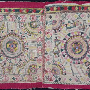 Può includere: Una coppia di quadrati di tessuto beige con ricami intricati in tonalità di rosa, giallo, verde e blu. I quadrati sono uniti da un bordo rosso.