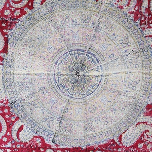 May include: A detailed textile with a central circular design in shades of blue, white, and purple, surrounded by a red paisley pattern. The intricate patterns and colors create a visually rich and decorative piece.