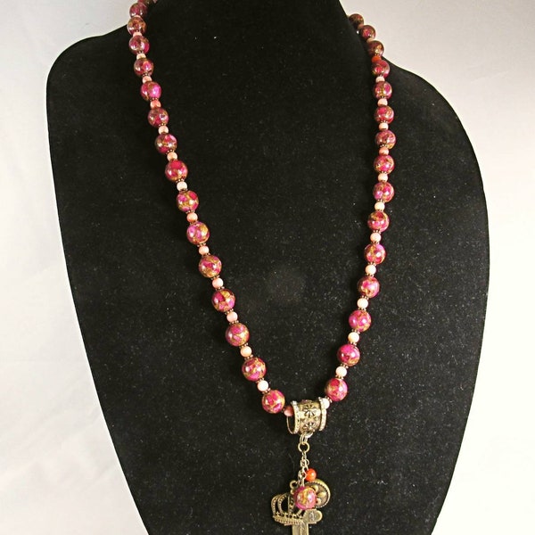 Necklace and earring set. Compressed glass beads in muti-rose hues. It has a bronze and rhinestone ring holding multiple pendants!